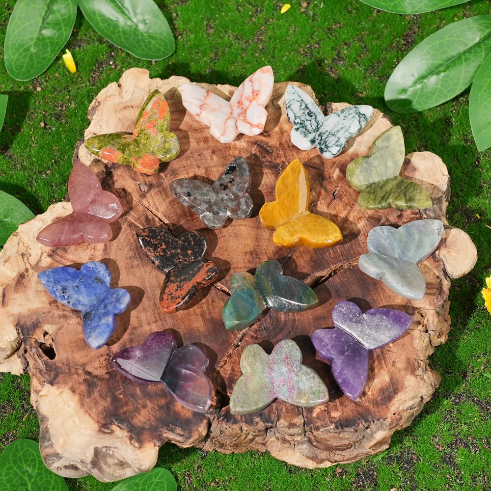 Colorful polished crystal butterfly carvings resting on a palm against a blurred green background