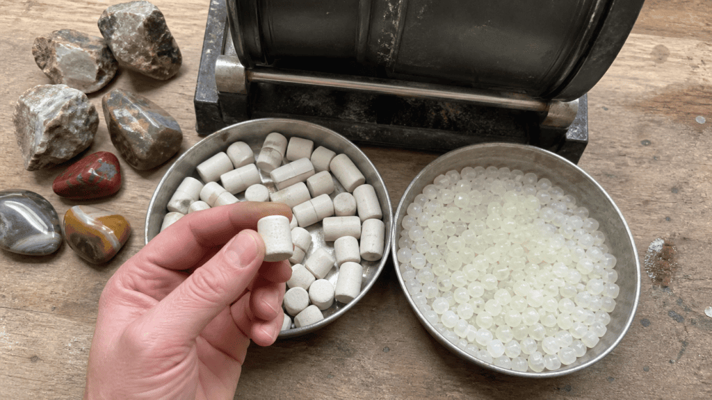 Assorted rock tumbling media including ceramic cylinders and plastic pellets used for protecting stones during the grit stages.