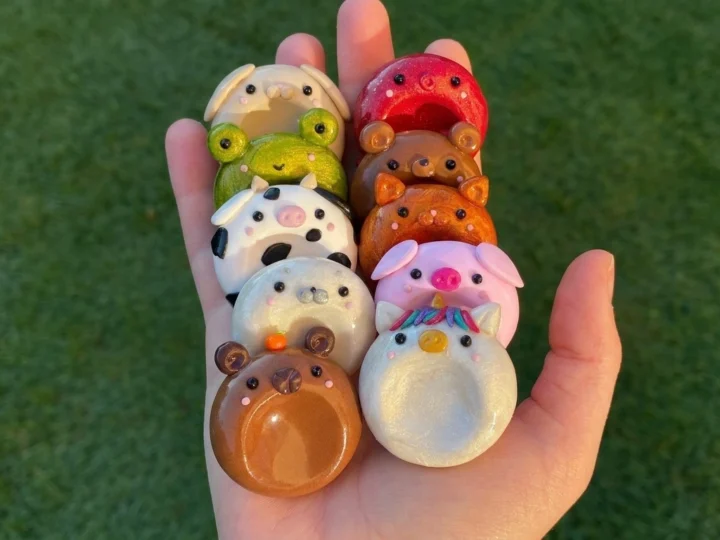 DIY clay worry stones in all ten animal designs, illustrated on a linen surface
