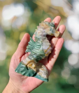 Green and cream stone seahorse with a curved neck, ribbed belly, rear fin, and curled tail